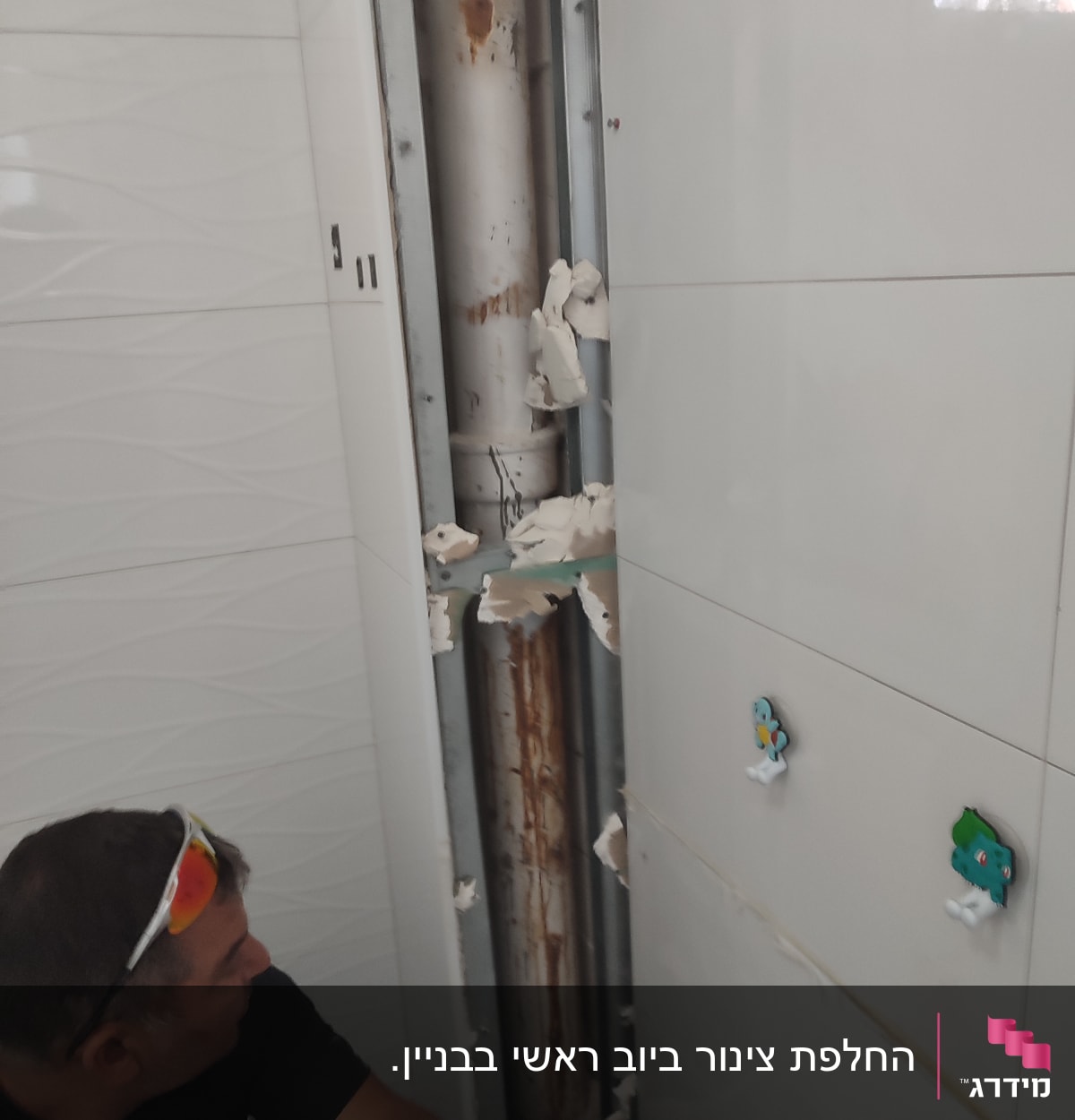 איש עם כפפות כתומות מתקן צינור חשוף בקיר